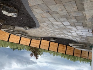 Wide multi-tone paver patio with curving black-bordered planter beds