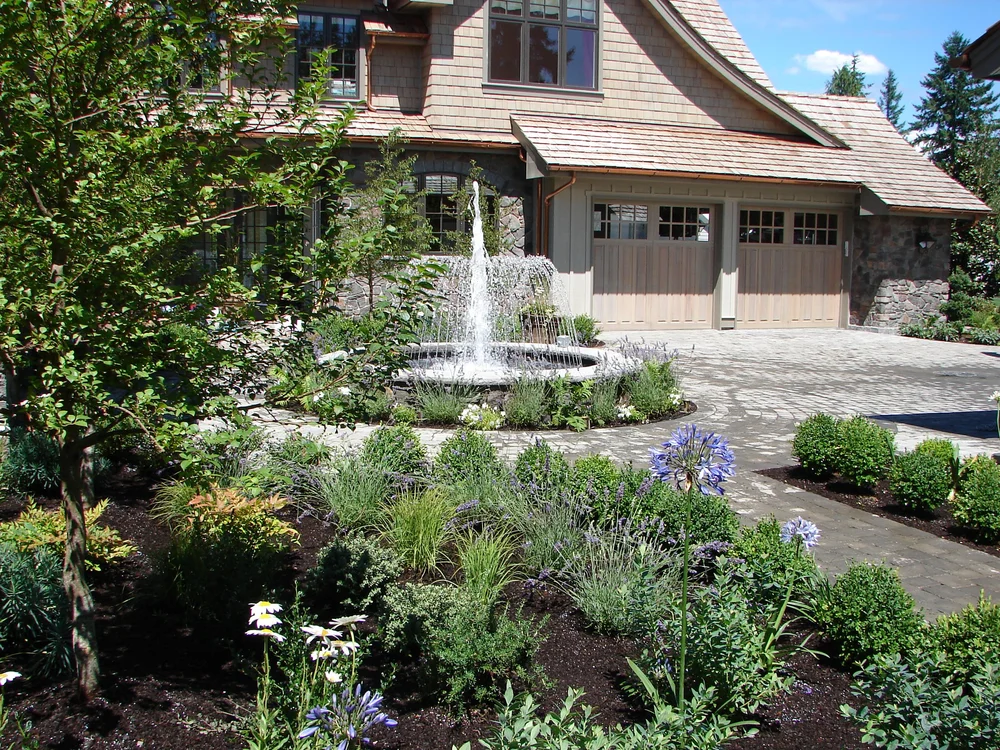 A finished front yard with a fountain and full plantings